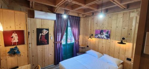 a bedroom with wooden walls and a bed and a window at Hotel London in Tirana