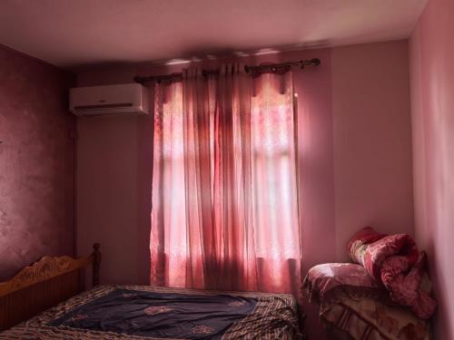 a bedroom with two beds and a window with red curtains at Soothing home in Brisée Verdière