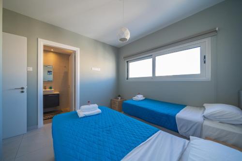 two beds in a room with a window at Majestic Sunset Salt Lake Views 300m From Beach in Larnaka