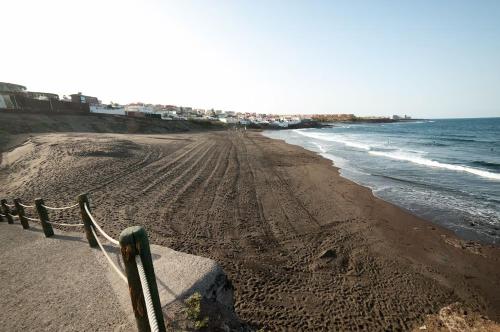 a sandy beach with a fence next to the ocean at La Brisa by Gran Canaria Homes in Playa del Hombre