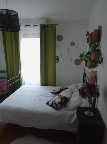 Cette chambre comprend un lit blanc avec des rideaux verts et une fenêtre. dans l'établissement La maison verte, à Miramont-de-Comminges