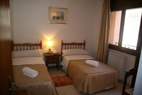 a bedroom with two beds and a lamp and a window at Gaspà in Ordino