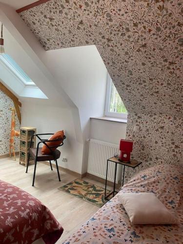 a attic room with a bed and a chair and a window at Maison au bord de l'eau in Saint-Brieuc