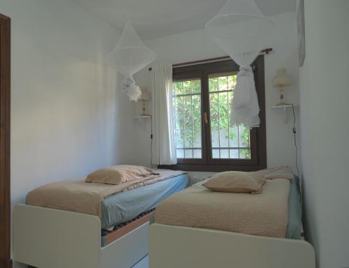 two beds in a room with a window at Casa Buenaventura in Calonge