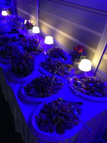 a buffet line with plates of food in blue lights at New Aegli Resort Hotel in Poros