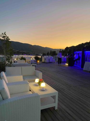 a patio with white couches and a table with lights at New Aegli Resort Hotel in Poros