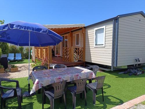 stół i krzesła z parasolem i domem w obiekcie L'incontournable Tout Confort Camping Siblu w Fréjus