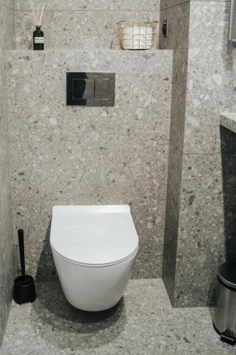 a bathroom with a white toilet in a stone wall at Arkada Wadowice in Wadowice