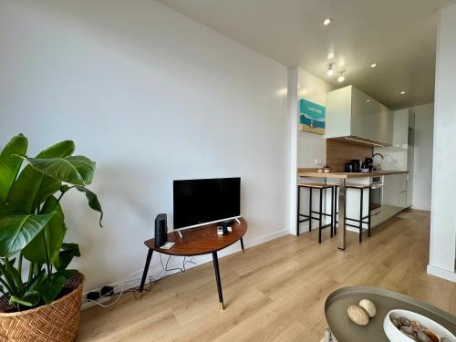 a living room with a table with a television on it at Azur à la Chaume in Les Sables-dʼOlonne