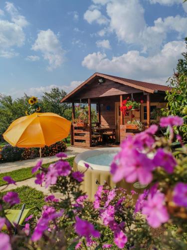 a house with a pool and an umbrella and flowers at Cottage La Sierra with JACUZZI in Korenica