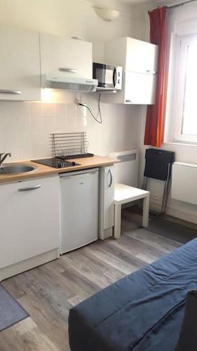 une petite cuisine avec des armoires blanches et un évier dans l'établissement Studette moderne, cosy et équipée en plein cœur de Versailles!, à Versailles