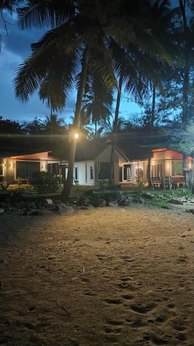a house with palm trees on the beach at night at Baan rabianglay 2 in Ban Hin Sam Kon