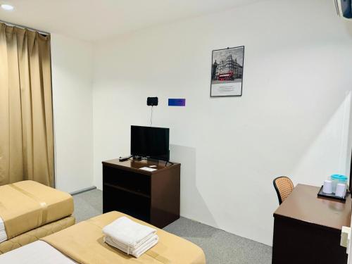 a room with a bed and a desk with a tv at Shangg INN in Ipoh