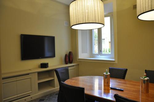 a dining room with a table and a flat screen tv at Hotel Patria in Pistoia