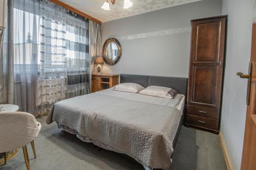 een slaapkamer met een bed, een spiegel en een raam bij Villa Asesor in Gdańsk