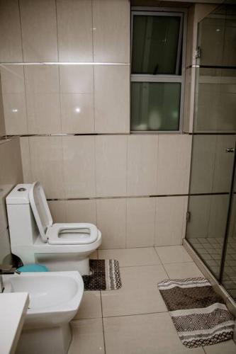 a white bathroom with a toilet and a shower at Seaside retreat for urban explorers above Mall in Maputo