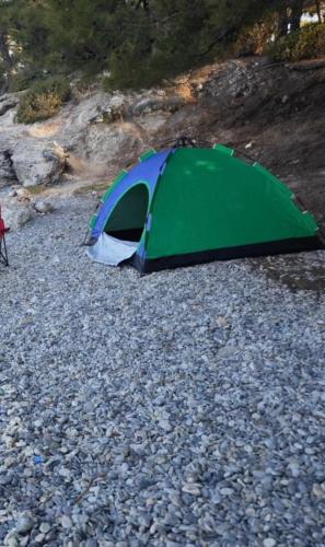 une tente verte et bleue sur un sol rocheux dans l'établissement Night Beacon, à Chèvreville