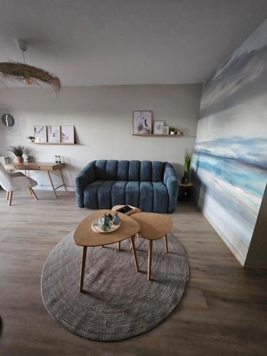 un salon avec un canapé bleu et une table basse dans l'établissement Le cocon du voyageur, à Bruay-la-Buissière