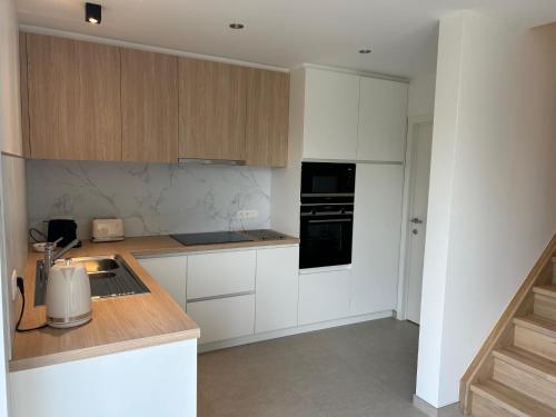 a kitchen with white cabinets and black appliances at Vakantiewoning Laurijn in Bilzen