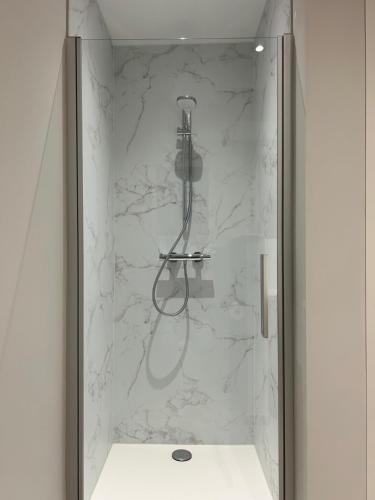 a bathroom with a shower with white marble walls at Vakantiewoning Laurijn in Bilzen