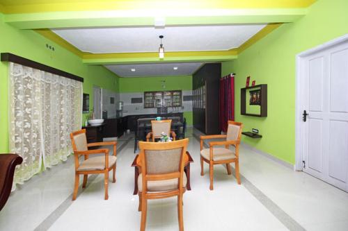 a living room with green walls and a table and chairs at RAMRA Homestay Madikeri in Madikeri