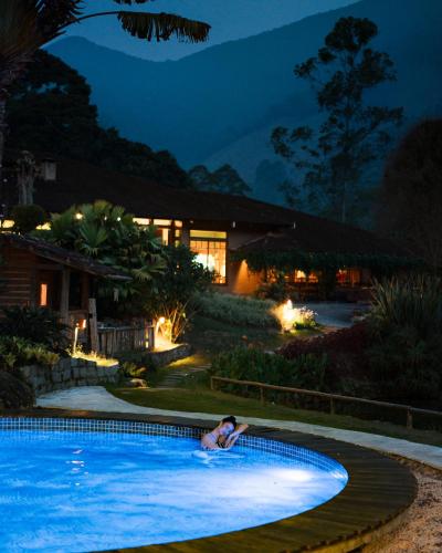 a woman laying in a swimming pool at night at Parador Lumiar Boutique Hotel & Spa in Lumiar