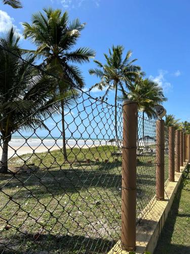 a chain link fence with palm trees behind it at Casa Águas de Olivença - Pé na Areia in Olivença