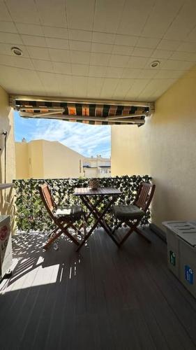 a patio with two chairs and a table in a room at Beachfront apartment with a pool- Parede in Parede