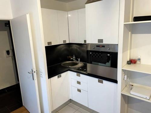 une cuisine blanche avec un évier et une cuisinière dans l'établissement Appartement très fonctionnel avec PARKING, à Aubervilliers