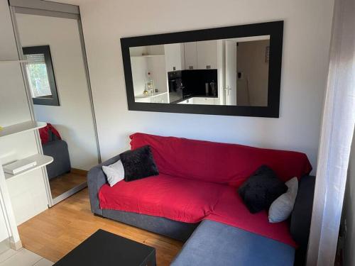 - un canapé rouge dans le salon avec un miroir dans l'établissement Appartement très fonctionnel avec PARKING, à Aubervilliers