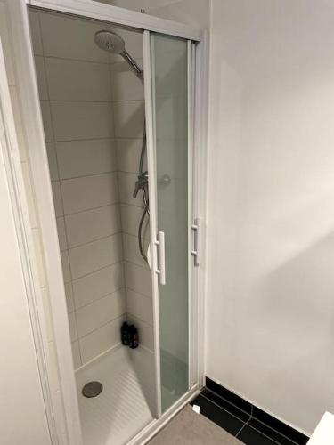 une douche avec une porte vitrée dans une salle de bain dans l'établissement Appartement très fonctionnel avec PARKING, à Aubervilliers
