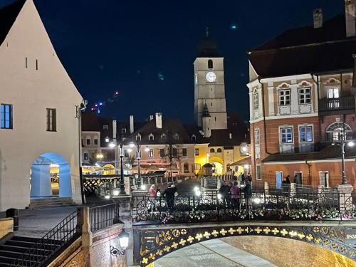 Una ciudad de noche con un puente y una torre de reloj. en Bridge View Studio, en Sibiu