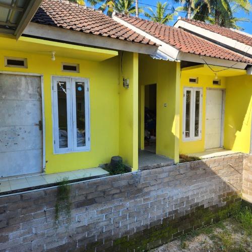a yellow house with a red roof at Mysterieus Guest House in Pawenang