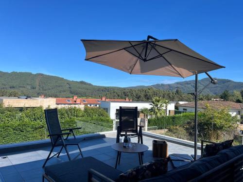 a patio with an umbrella and a table and chairs at Casa con Vistas al Paisaje y Encanto en el Corazón del País Vasco,España in Mungia