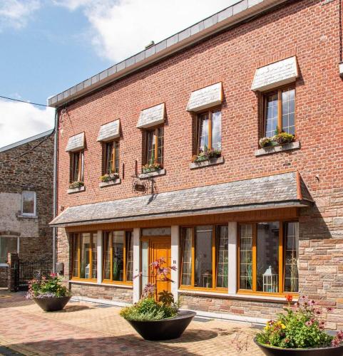 a brick building with windows and plants in front of it at Gite les bons amis in Plombières