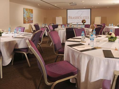 a conference room with tables and chairs and a screen at Fraser Suites Seef Bahrain in Manama