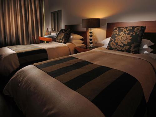a hotel room with two beds and a lamp at Fraser Suites Seef Bahrain in Manama