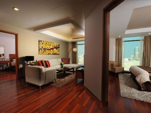 a room with a bed and a living room with a couch at Fraser Suites Seef Bahrain in Manama