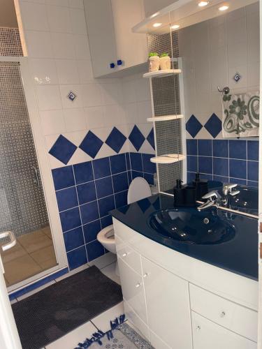 Un baño azul y blanco con lavabo y ducha. en Bali, en Saint-Martin-Lalande