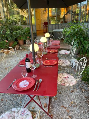 a red table with red plates and wine glasses at La Dommerie-Gite de charme in Domme