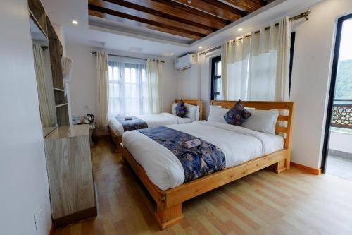 a bedroom with two beds and a large window at Thumki Resort, Balthali in Panauti