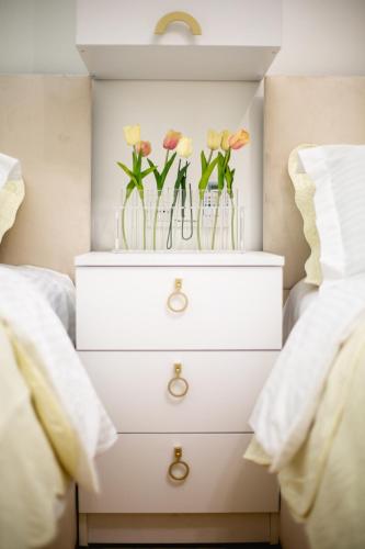 a white dresser with vases of flowers on it at Golden Palace in Kutaisi