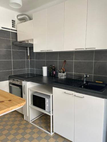 une cuisine avec des armoires blanches et un évier dans l'établissement Chartreux, à Marseille