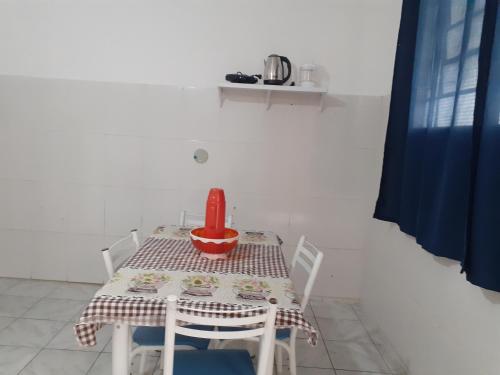 a table with two chairs and a red container on it at Casa a 270 metros da basilica in Aparecida