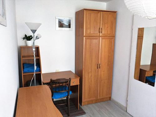 a room with a desk and a wooden cabinet at Słoneczny Pokój w bloku na 1 p dla 1 Niepalącej Osoby od 1 do 12 miesięcy in Kraków