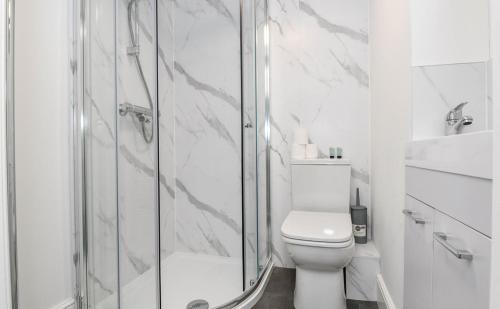 a white bathroom with a shower and a toilet at Mill Bridge in Skipton