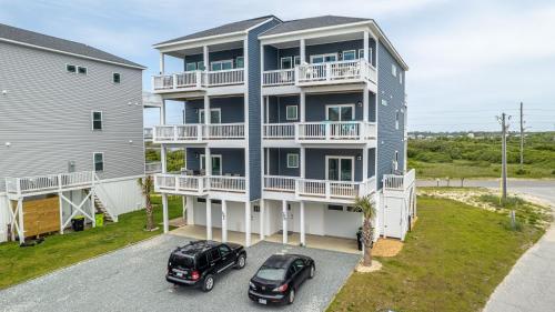 een appartementencomplex met twee auto's op een parkeerplaats bij Unobstructed Ocean Views - Hot Tub - Sandy Path to Beach in North Topsail Beach