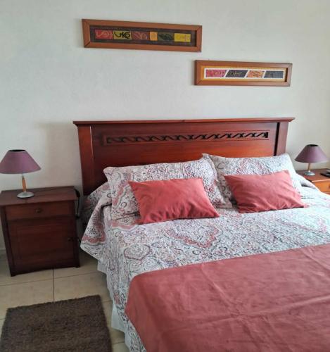 a bedroom with a bed with two red pillows at Bahia Pelícanos Horcón depto. en primera línea in Puchuncaví