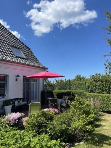 a house with a patio with a red umbrella at Deichhof Whg 23 in Dunsum