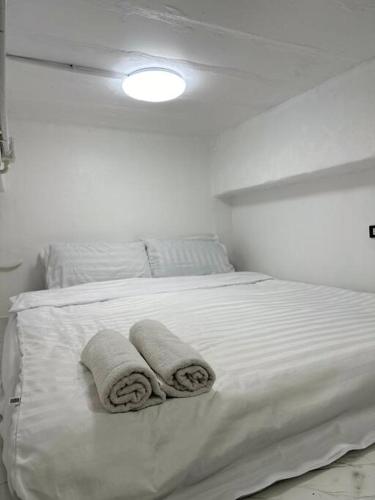 a white bedroom with two towels on a bed at Megun 10 Duplex in Bangkok
